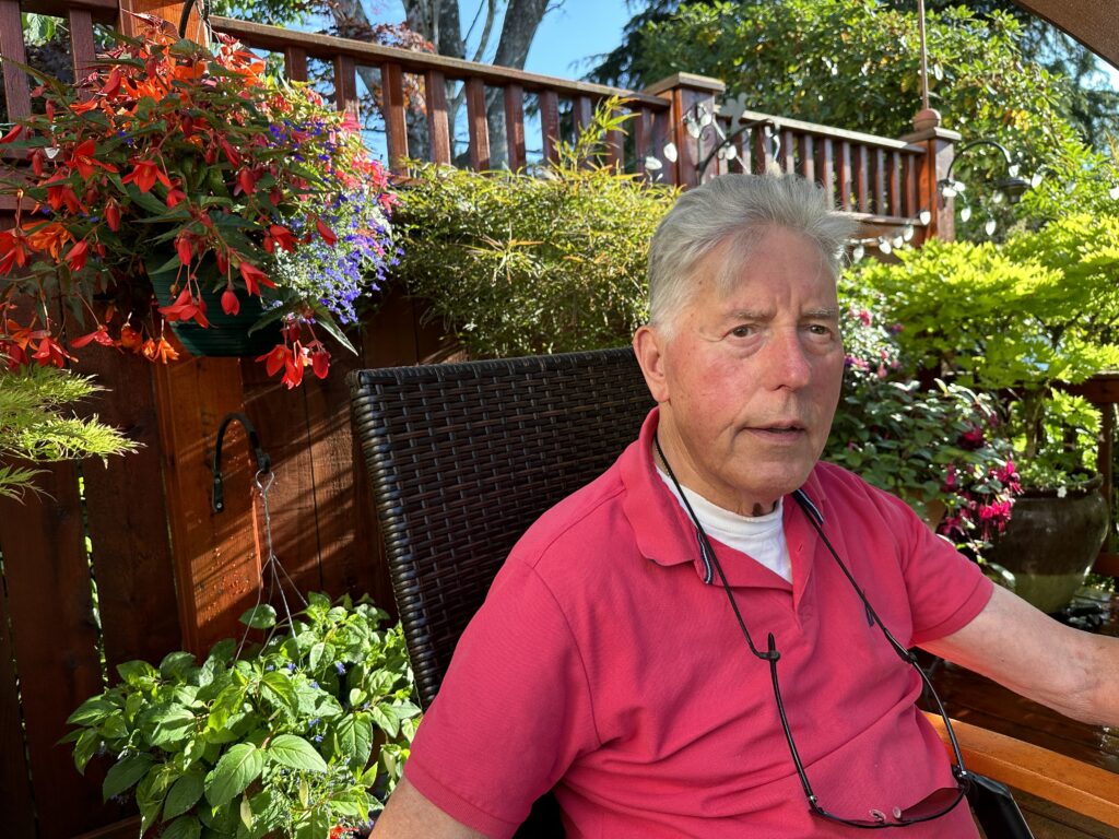 Man sitting in a chair in front of a lush garden
