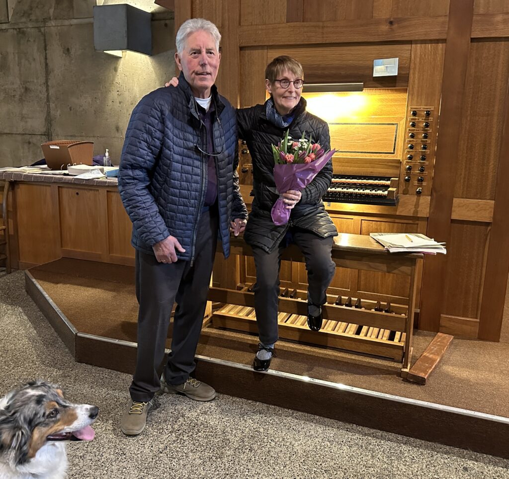 A woman is presenting flowers to a man in front of an organ in a church