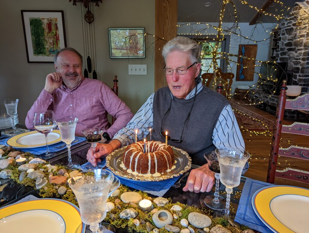 two men sit at dinner table with birthday cake